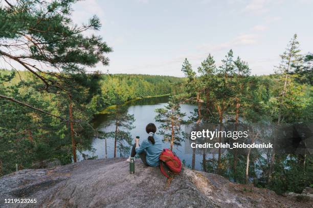 woman looking at lake in finland and drinking tea - finland happy stock pictures, royalty-free photos & images