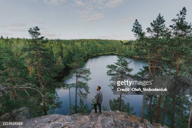 mann zu fuß in der nähe des sees im sommer - finnland stock-fotos und bilder
