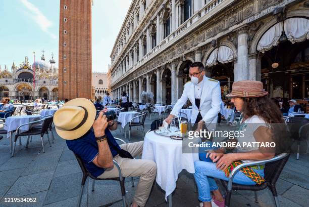 Customer takes a photo of a waiter at the terrace of the 18th Century Cafe Florian on June 12, 2020 on St. Mark's Square in Venice, which reopens...