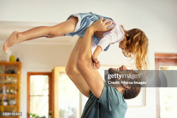 happy father carrying daughter in mid-air at home - picking up child stock pictures, royalty-free photos & images