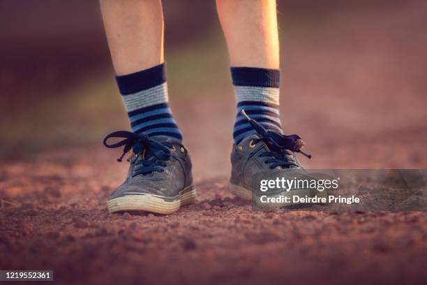 child's feet wearing blue shoes and socks on a dusty road at dusk - lost sock stock pictures, royalty-free photos & images