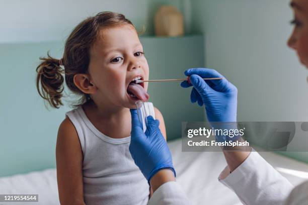 kleines mädchen während eines mund-swab-medizintests im krankenhaus - blauer handschuh stock-fotos und bilder