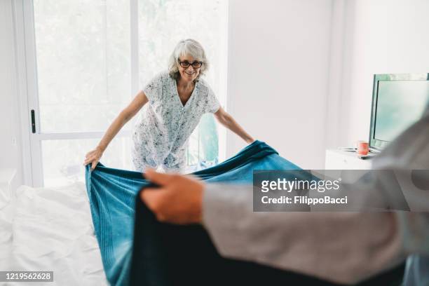 mature couple making the bed together - make a change stock pictures, royalty-free photos & images