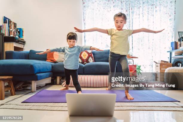 little sibling enjoy online yoga class with laptop computer at home. - balancing child stock pictures, royalty-free photos & images