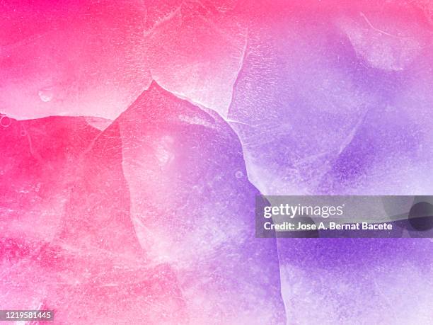 full frame of the textures formed of a block of cracked ice on a pink color background. - soft drink stock-fotos und bilder