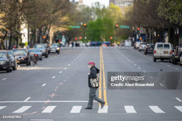 Woman wearing a protective mask and gloves carrying a “New Yorker” tote bag walks along an empty street on April 16, 2020 in New York City, United...