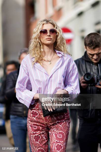 Romee Strijd wears a mauve pale purple shirt, a golden necklace, red pants with floral print, outside Etro, during Milan Fashion Week Fall/Winter...