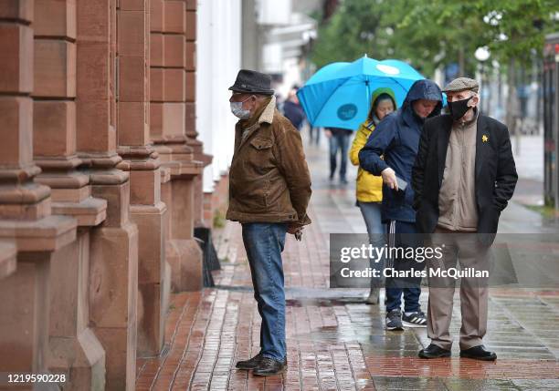 Customers queue on the high street as retail and non essential shops reopened on June 12, 2020 in Belfast, Northern Ireland. After being shuttered...