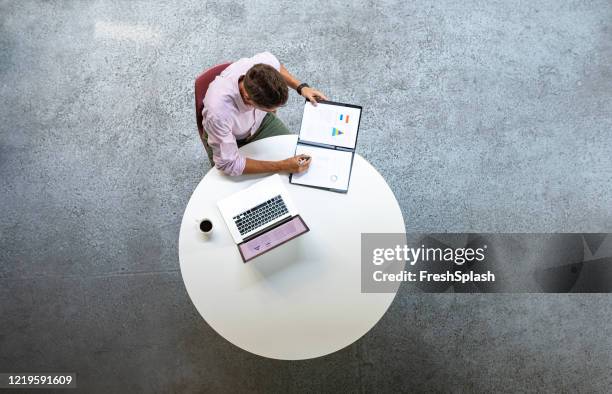 overhead-foto von geschäftsmann, der an einem runden tisch arbeitet - draufsicht büro stock-fotos und bilder