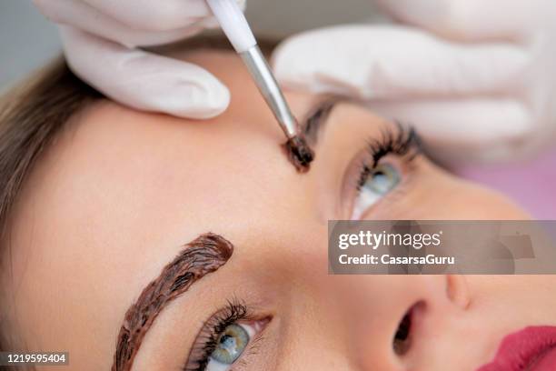 photo en gros plan de beautician applying dye on woman’s eyebrows - photo stock - sourcils photos et images de collection