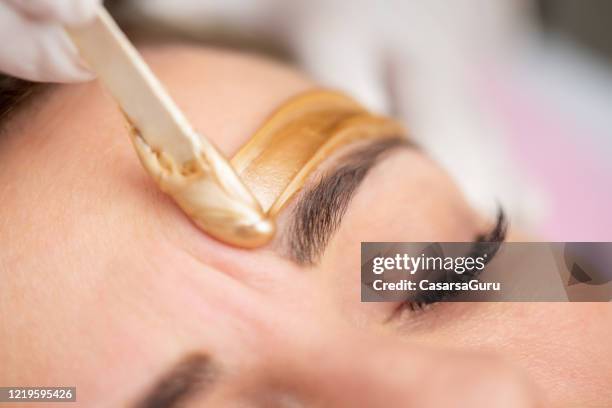 het toepassen van gouden gekleurde was met spatel op het gezicht van de vrouw - voorraadfoto - hair removal stockfoto's en -beelden