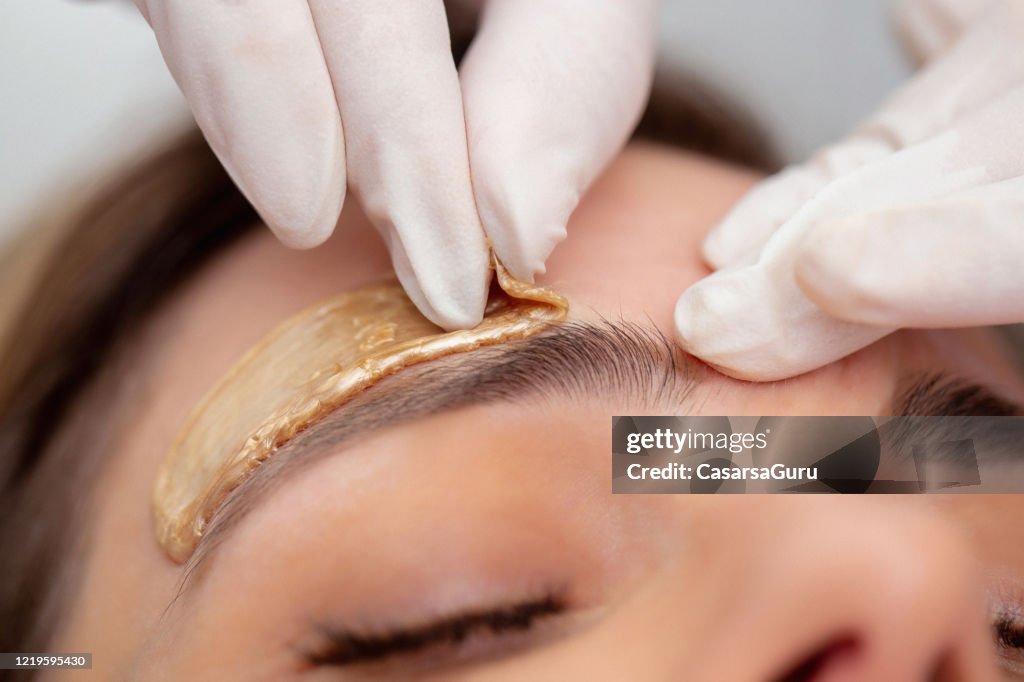 Kosmetikerin Entfernen Augenbrauen Haare mit Wachs - Stockfoto