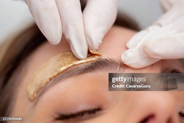 beautician extracción de pelos de cejas con cera - foto de stock - waxing hair removal fotografías e imágenes de stock