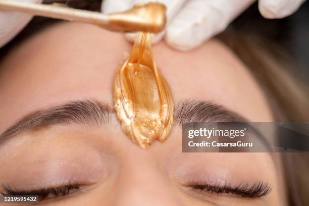 applying facial wax between eyebrows - stock photo - turner contemporary stock pictures, royalty-free photos & images