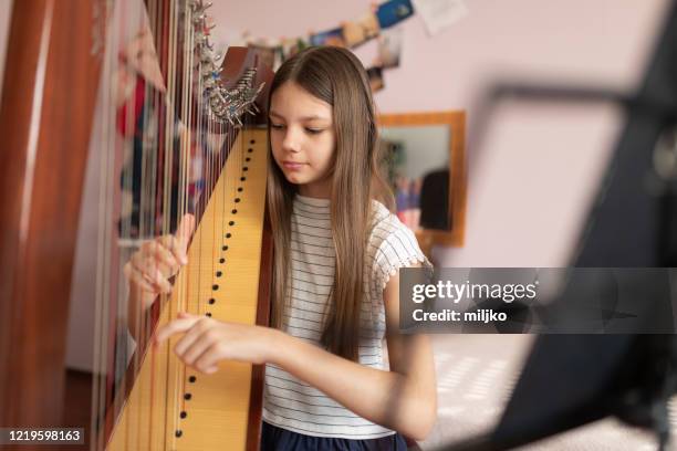 chica tocando arpa en casa - arpa fotografías e imágenes de stock