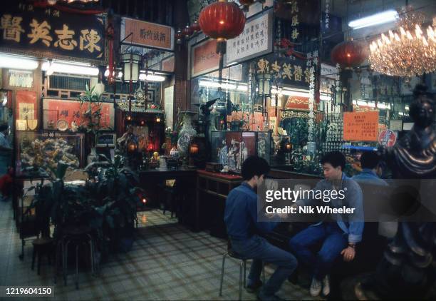 Traditionally furnished with traditional Chinese furniture and ornaments a chiropractor works on a patient in his clinic in Hong Kong circa 1985;