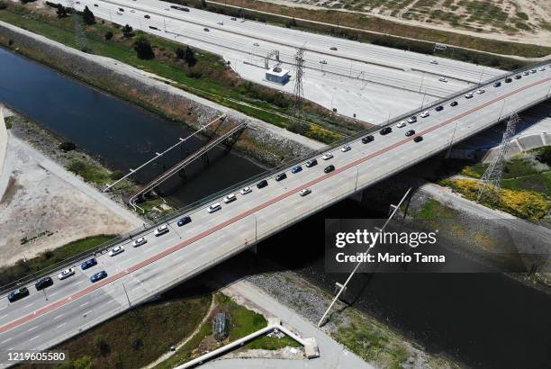 An aerial drone view of cars lined up to receive food distributed by the Los Angeles Regional Food Bank, with light traffic on the 405 freeway below...