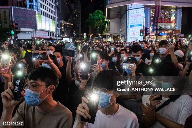 Pro-democracy activists hold up their mobile phone torches as they sing during a rally in the Causeway Bay district of Hong Kong on June 12, 2020. -...