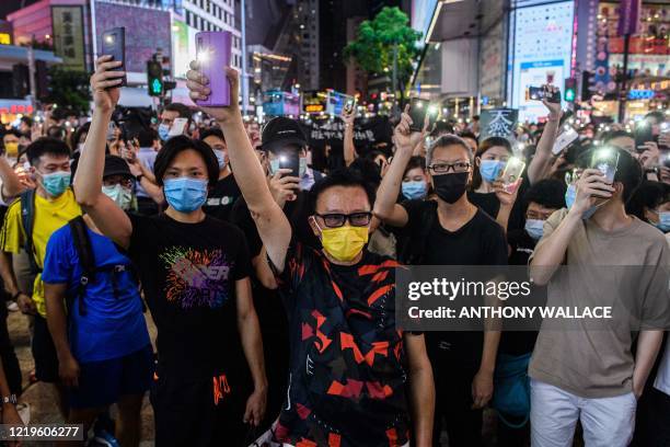 Pro-democracy activists hold up their mobile phone torches as they sing during a rally in the Causeway Bay district of Hong Kong on June 12, 2020. -...