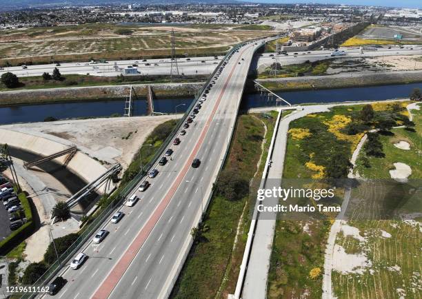 An aerial drone view of cars lined up to receive food distributed by the Los Angeles Regional Food Bank, with light traffic on the 405 freeway below...