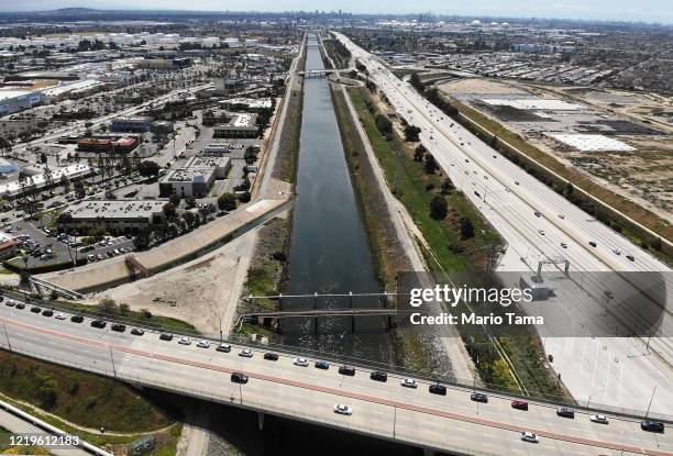 An aerial drone view of cars lined up to receive food distributed by the Los Angeles Regional Food Bank, with light traffic on the 405 freeway below...