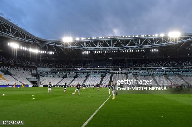 General view shows Juventus players warm up in an empty stadium prior to the Italian Cup semi-final second leg football match Juventus vs AC Milan on...