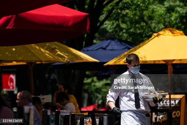 Waiter at Mon Ami Gabi, a French restaurant in Maryland, wears a protective face mask as they serve customers outdoors amid the coronavirus pandemic...