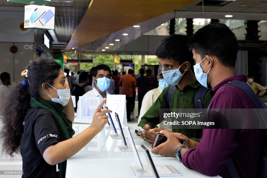 Salesmen at a mobile store wearing face masks as a...