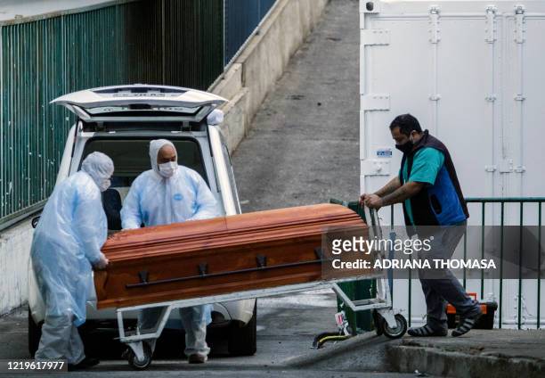 Employees of a funeral parlour carry the coffin of a COVID-19 victim into a vehicle, outside the Carlos Van Buren Hospital in Valparaiso on June 12,...