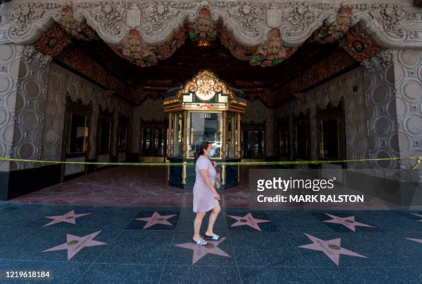 Woman walks past the El Capitan Theater which is closed due to the Covid-19 virus, on Hollywood Blvd, Hollywood, California on June 12, 2020. -...