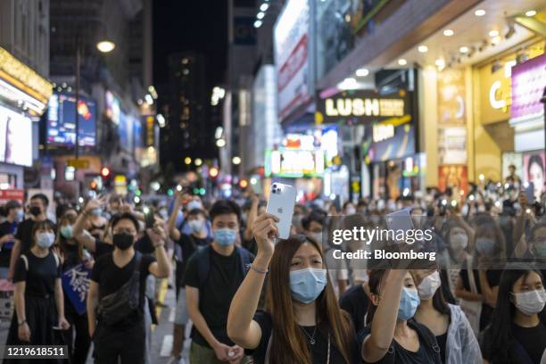 Demonstrators wearing protective masks shine lights from their smartphones during a protest in the Causeway Bay district of Hong Kong, China, on...