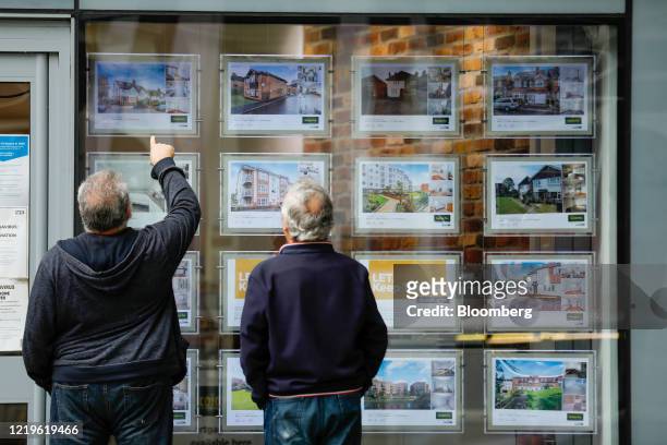 Pedestrians view displays in an estate agent's window in Guildford, U.K., on Friday, June 12, 2020. U.K. House prices fell the most in more than a...