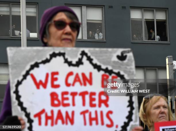 Woman holds up a placard during a pro-refugee rights protest in Melbourne on June 13, 2020 as several asylum seekers who were evacuated for medical...