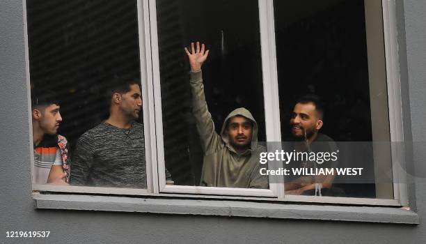 Asylum seekers gesture to protesters holding a pro-refugee rights rally from their hotel room where they have been detained in Melbourne on June 13...