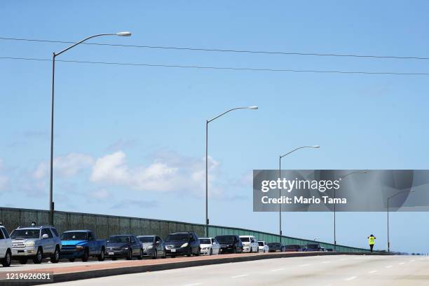 Volunteer walks as cars are lined up to receive food distributed by the Los Angeles Regional Food Bank amidst the coronavirus pandemic on April 18,...