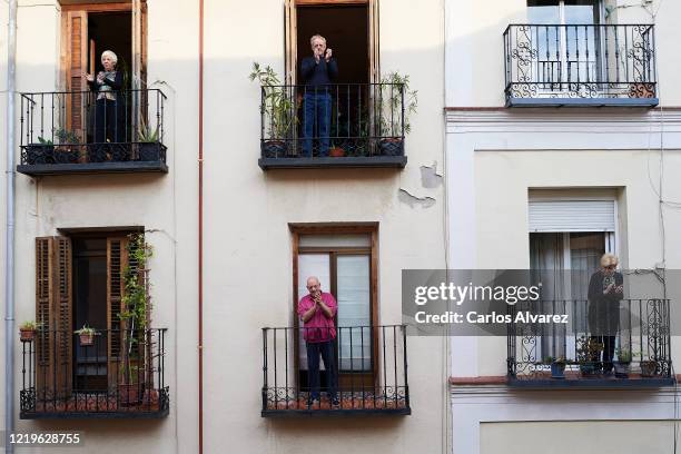 People on their balconies applauding to pay tribute to healthcare workers struggling to fight the coronavirus pandemic on April 18, 2020 in Madrid,...