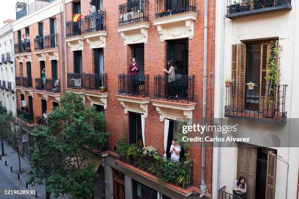 People on their balconies applauding to pay tribute to healthcare workers struggling to fight the coronavirus pandemic on on April 18, 2020 in...