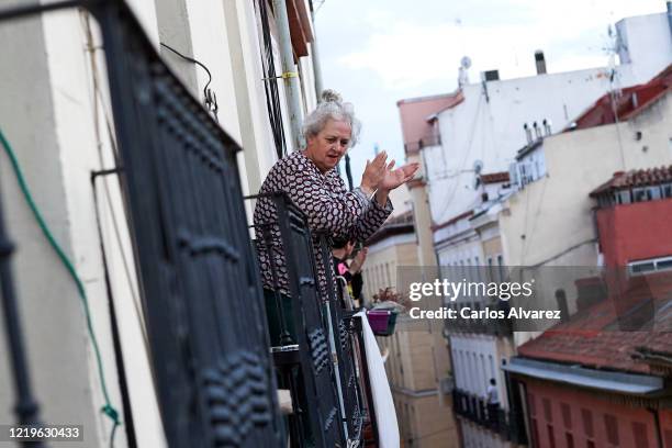 Woman on her balcony is seen applauding to pay tribute to healthcare workers struggling to fight the coronavirus pandemic on on April 18, 2020 in...