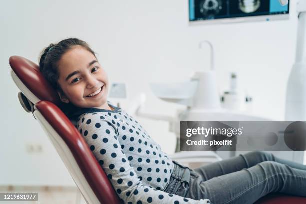 ragazza sorridente seduta sulla sedia del dentista - dentista bambini foto e immagini stock