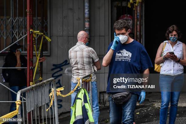 People tsand by the cordoned off entrance of a building on June 13, 2020 on Piazza Pecile in the Garbatella district of Rome, where at least 17 cases...