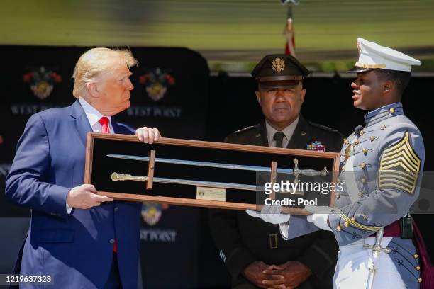 President Donald Trump is offered a class gift after speaking to West Point graduating cadets during commencement ceremonies at Plain Parade Field at...