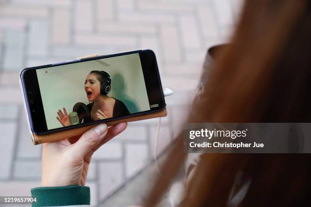 Japanese woman Noemi poses for a picture as she watches on her smartphone the live stream performance of Lady Gaga during the "One World: Together At...