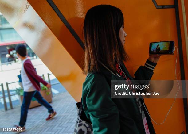 Japanese woman Noemi poses for a picture as she watches on her smartphone the live stream performance of Taylor Swift during the "One World: Together...