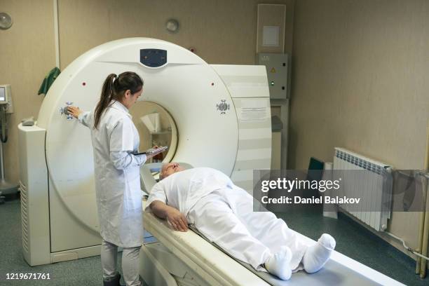 放射科醫生準備醫療掃描器工作。與病人交談,説明他為手術做好準備。 - pet scan machine 個照片及圖片檔