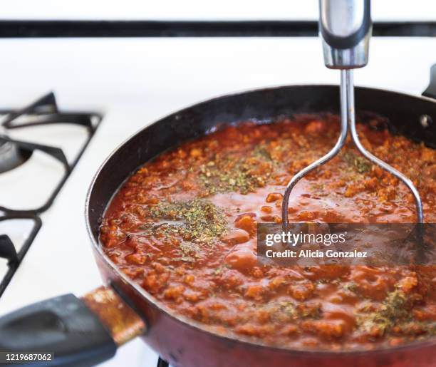 red meat sauce with italian seasoning cooking in skillet on white stove - orégano fotografías e imágenes de stock