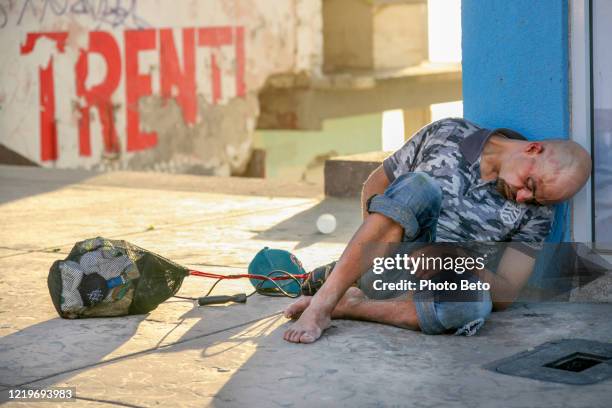 an apparently injured homeless man sleeps on a tijuana beach street near the us-mexico border wall - san diego landscape stock pictures, royalty-free photos & images