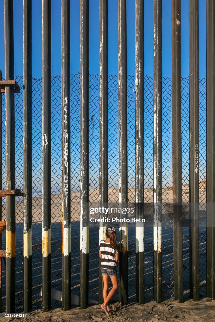 A girl looks through the steel wall on the US-Mexico border in Tijuana Beach