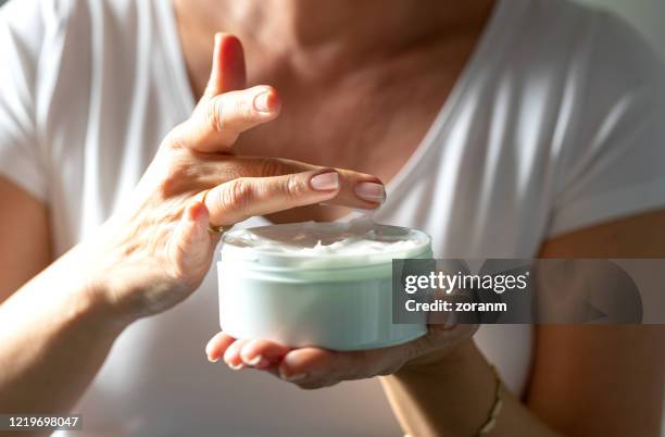 taking facial cream with finger from a jar - body lotion stock pictures, royalty-free photos & images