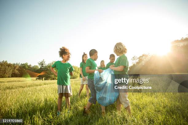 multiethnic group of children collecting waste. - mixed recycling bin stock pictures, royalty-free photos & images