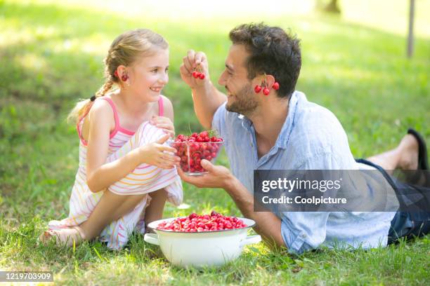 happy father with child eating cherries. - berry picker stock pictures, royalty-free photos & images